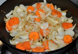 Положить раздавленные дольки чеснока, через полминуты – добавить нарезанные крупными перьями луковицы. Не снижая сильного огня, помешивая, обжаривать 3-4 минуты. Положить толстые кружки морковки, обжаривать столько же.