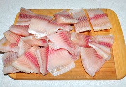 Рыбное филе (или тушки рыбы, которые позже будут разделаны) разморозить на полке холодильника, промыть, обсушить как можно тщательнее. Нарезать филе удобными для жарки и подачи кусками, приправить.